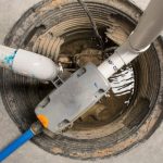 Sump pump system with pipes and water level, part of Maxwell-White Plumbing services for water management.